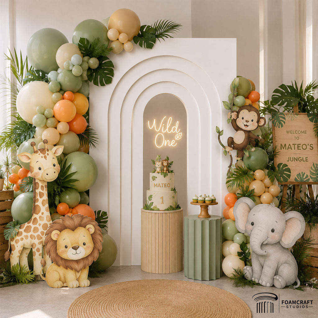 Layered arch backdrop decorated with jungle safari balloons, tropical leaves, animal cutouts, and birthday cake for a children’s jungle-themed party.